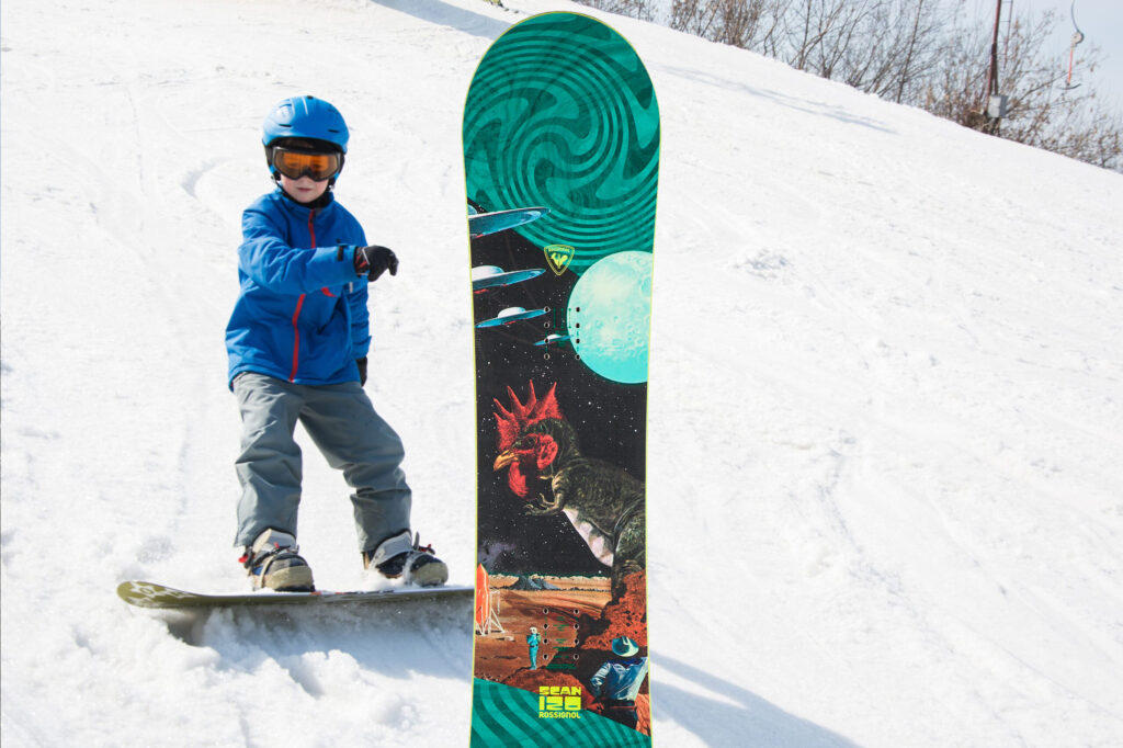 Image of the Kids or Junior Snowboard Rental Package on a background of a kid wearing a blue jacket snowboarding